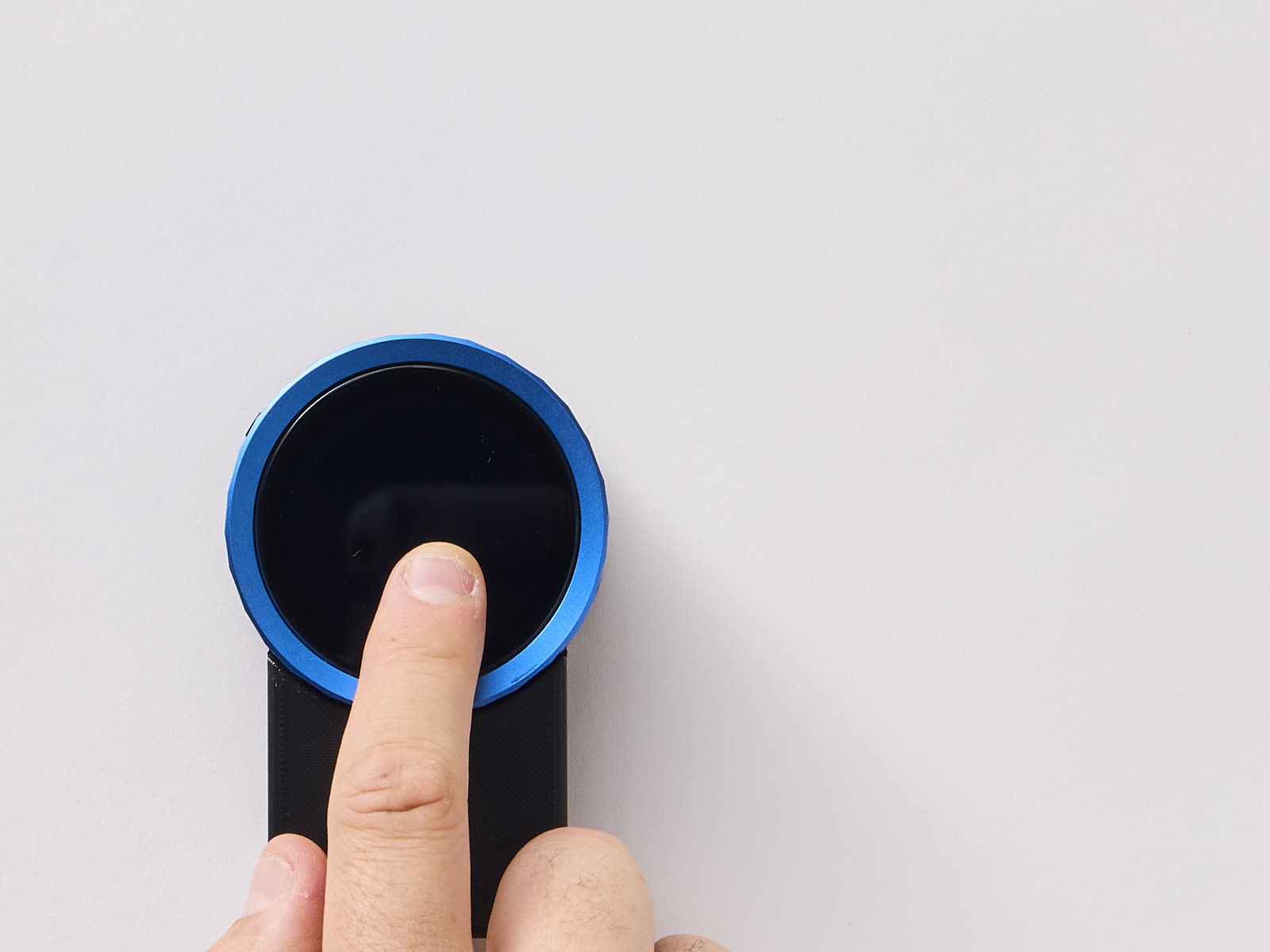 A finger pressing the button on the Trepo device to speak to it