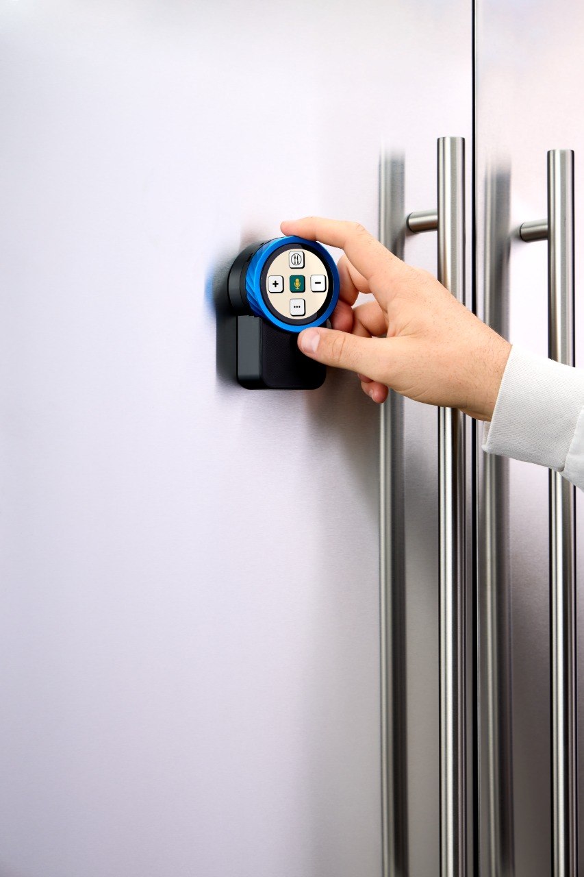 A hand turning the knob on the Trepo device mounted on a fridge door