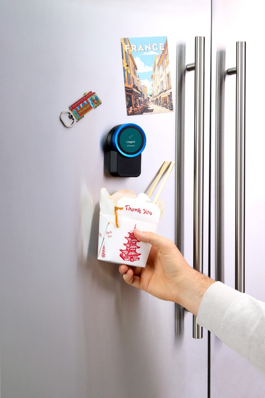 A takeout container held up to the Trepo device on a fridge door, which reads Logged — leftovers