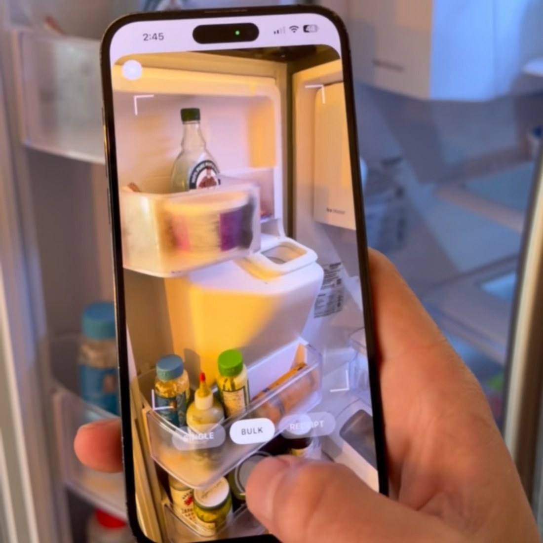 A phone held up to an open fridge, the Trepo camera framing the shelves to identify what's inside